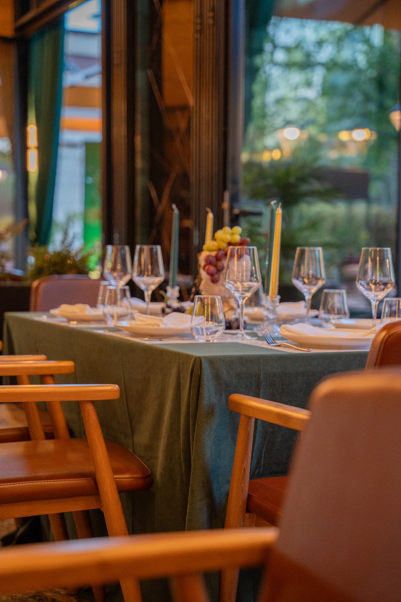 Green velvet table setting with candles and wine glasses beside the open terrace at ASADOR Tirana